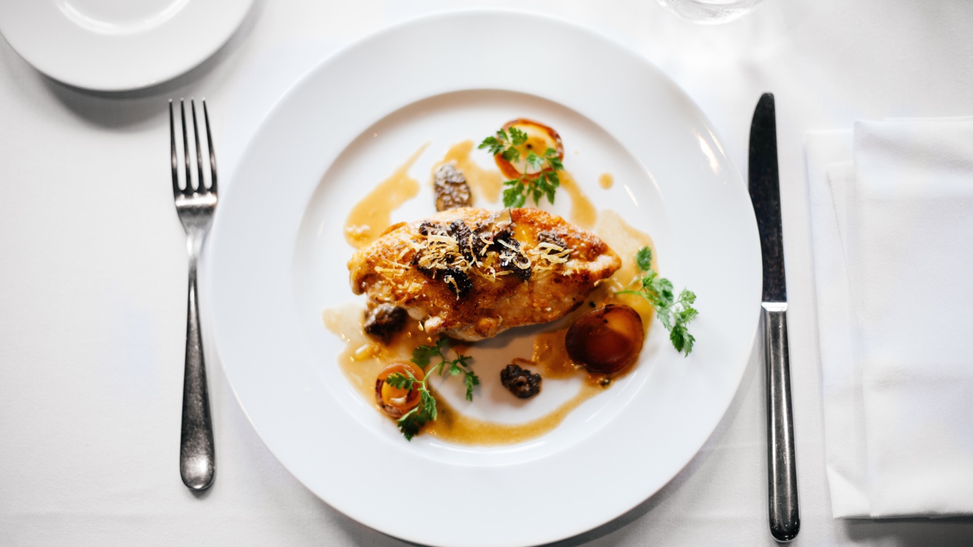 Кусок жареного мяса на большой белой тарелке 