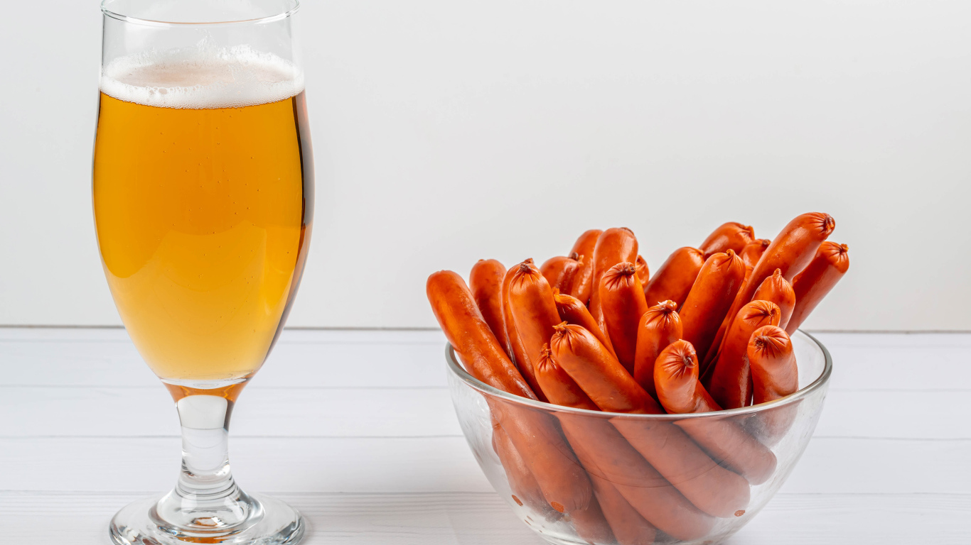 Вкусные сосиски на столе с бокалом пива