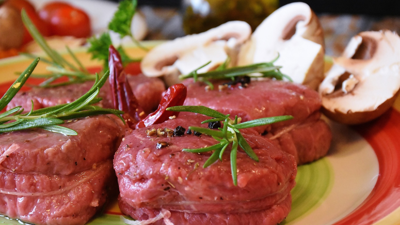 Свежее мясо маринуется со специями на столе с грибами