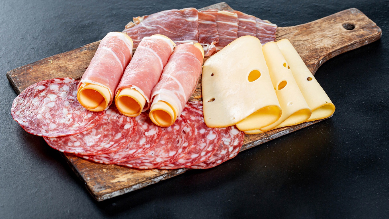 Рулеты из ветчины с сыром на столе с колбасой и мясом