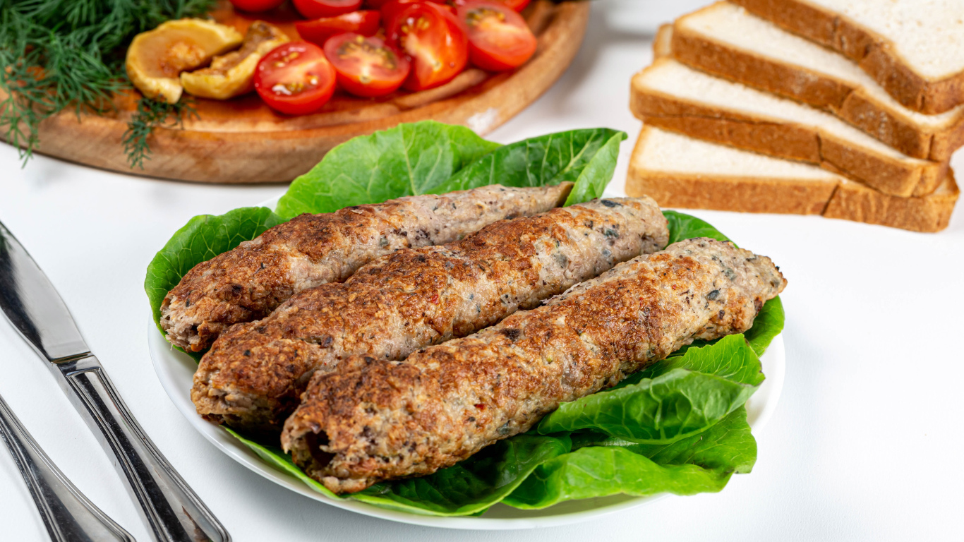 Мясное блюдо кебаб на столе с зелеными листьями 