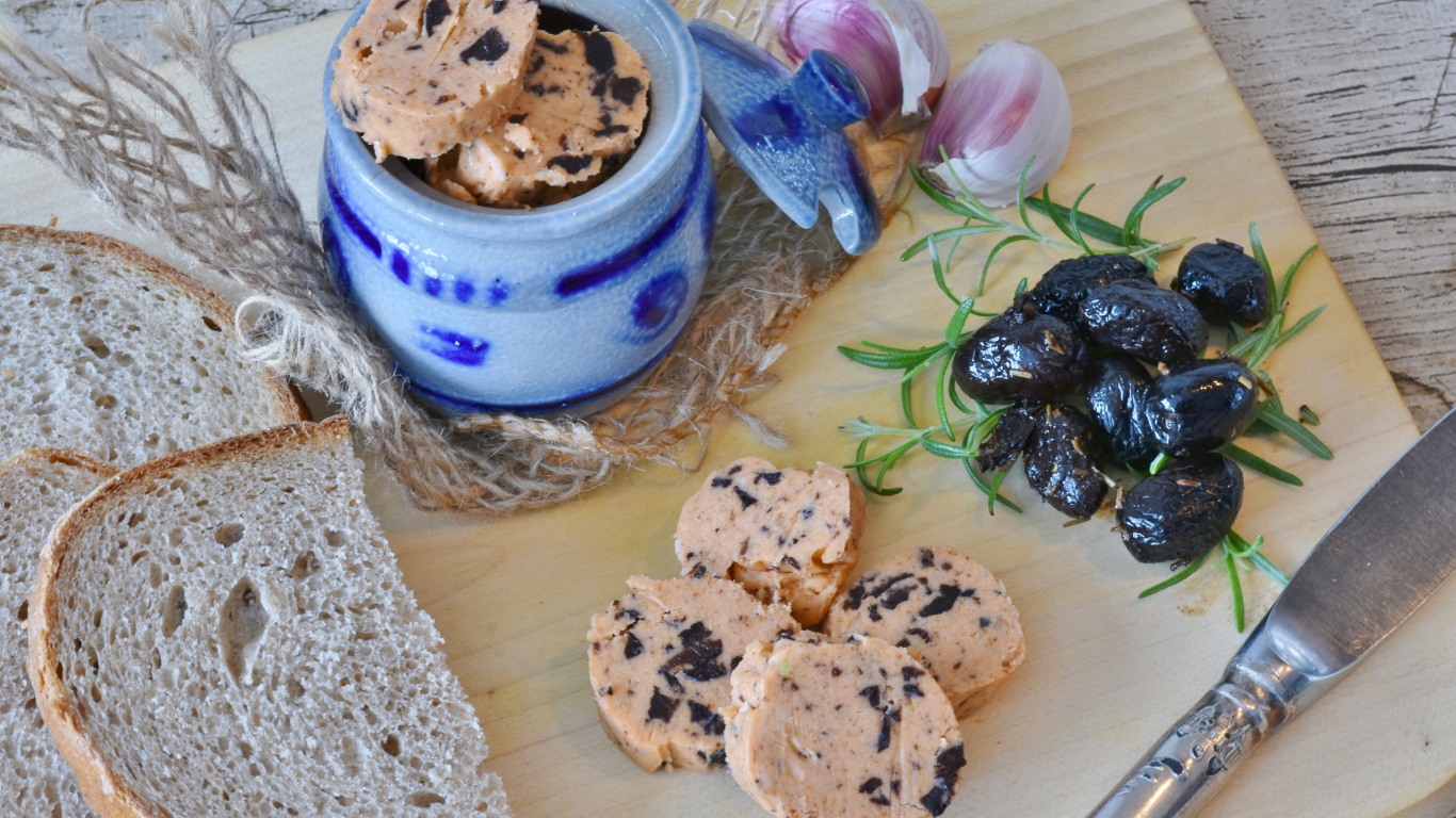 Колбаса с маслинами на столе с хлебом и чесноком