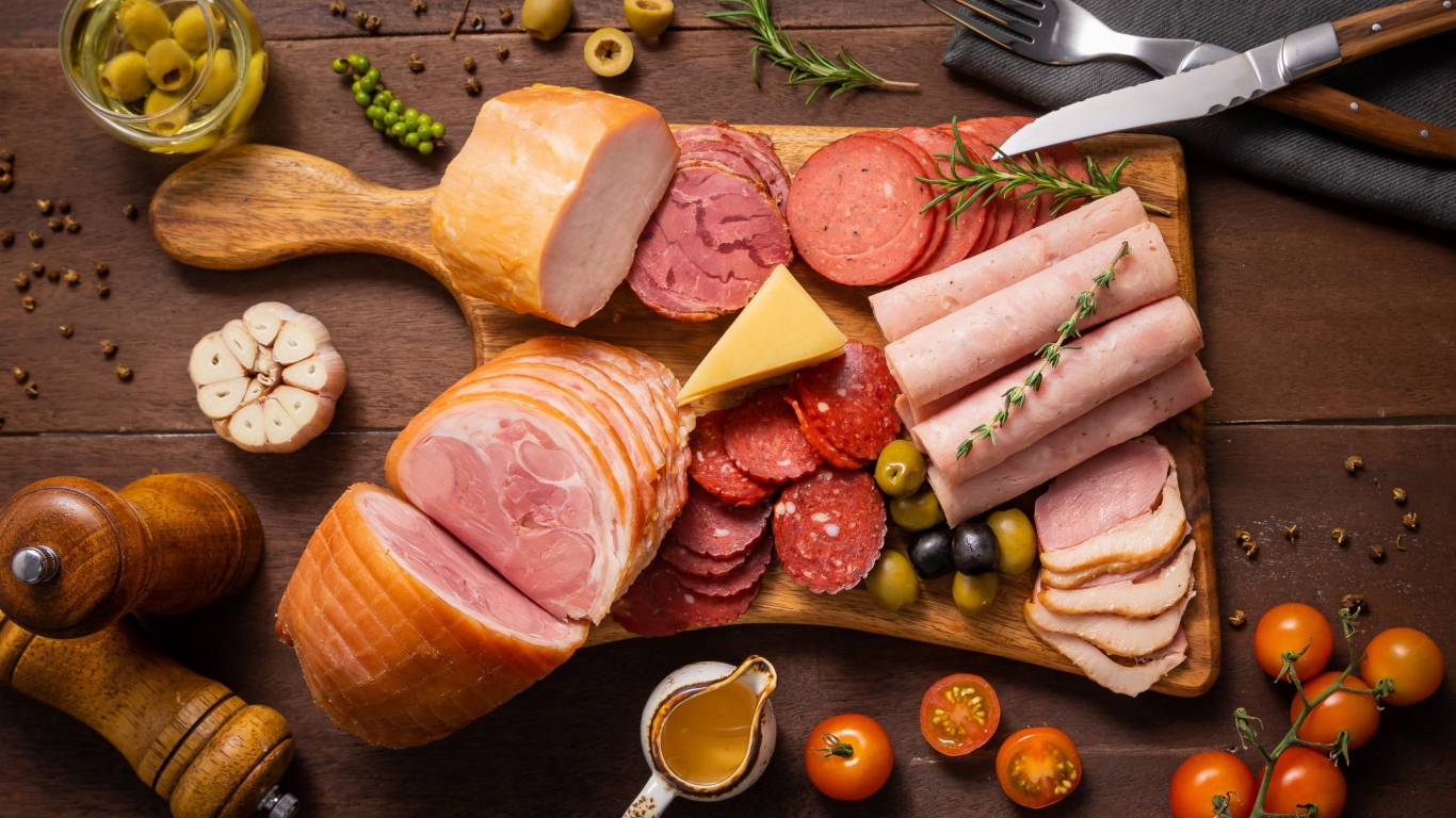 Колбасы и мясные продукты на доске со специями