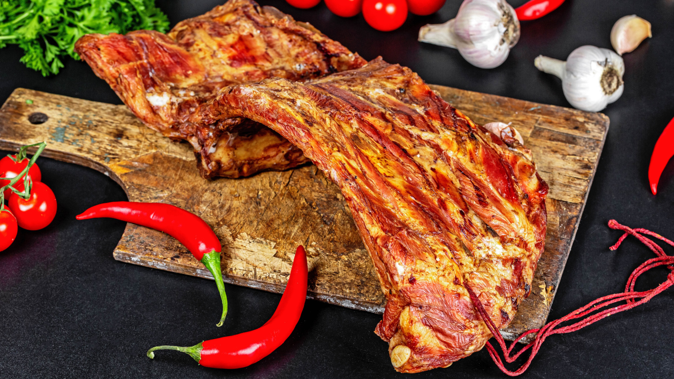 Копченые ребра на столе с красным перцем, чесноком и помидорами