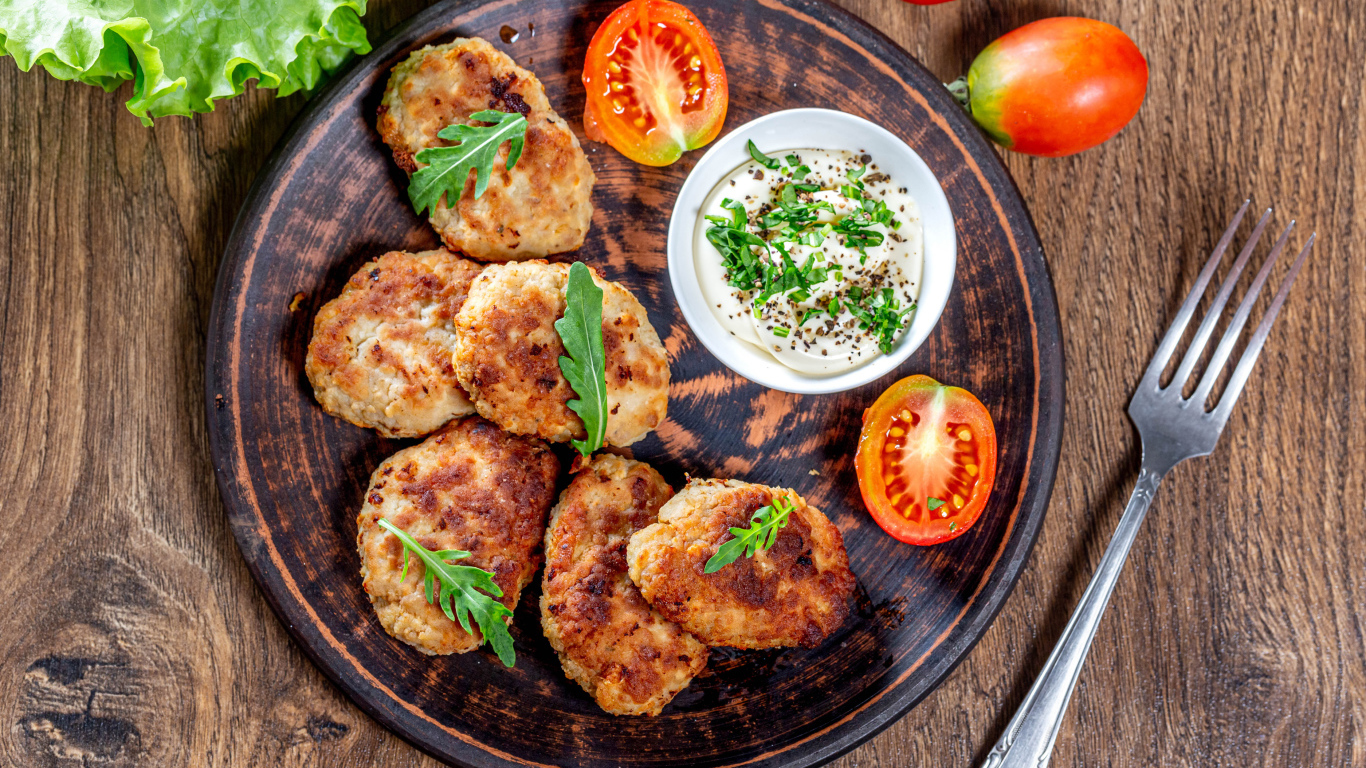 Вкусные котлеты на столе с соусом и помидорами