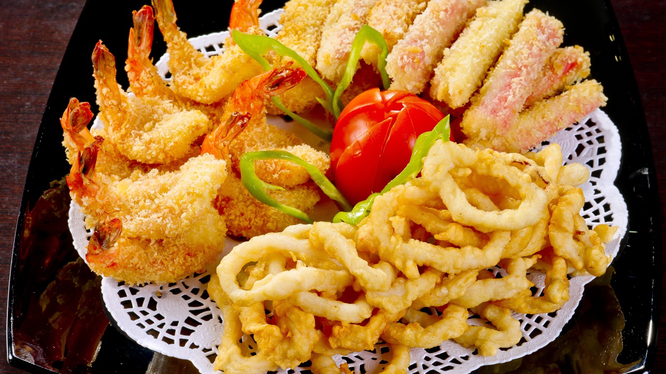 Морепродукты в кляре на тарелке с помидором