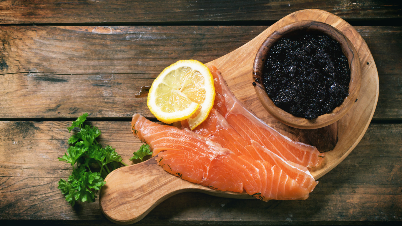 Кусочки красной рыбы с лимоном на столе с черной икрой 