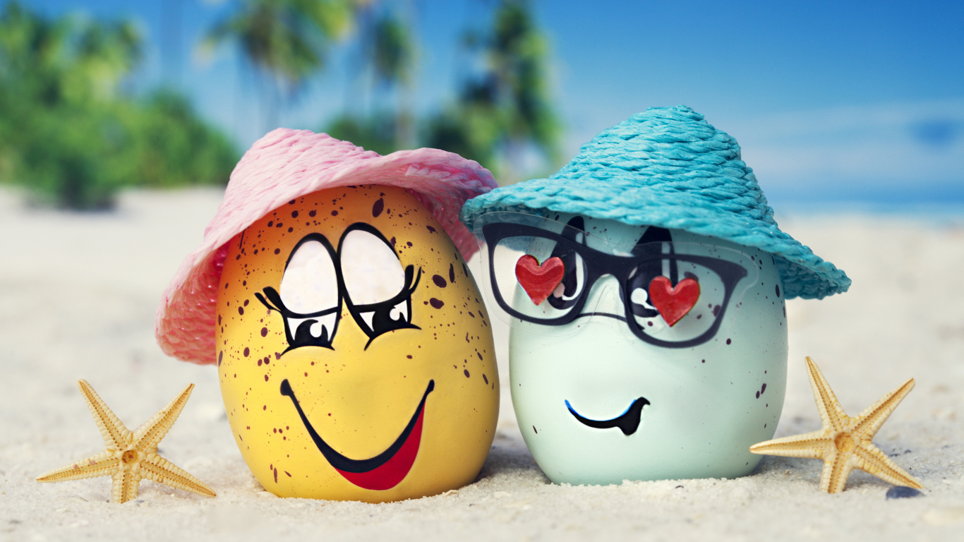 Два яйца в шляпах на песке с морскими звездами летом