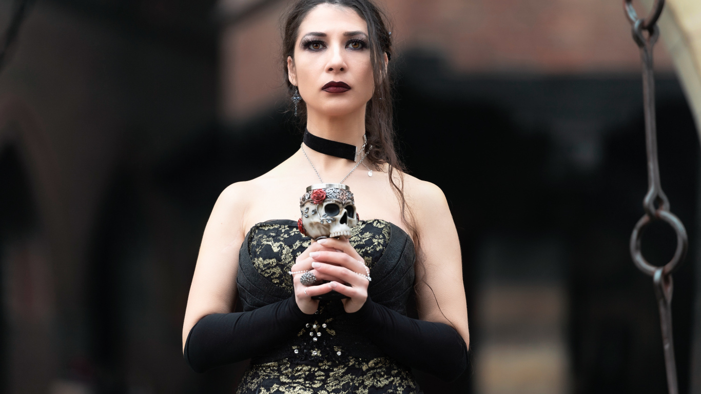 Девушка готка с бокалом - черепом в руках 