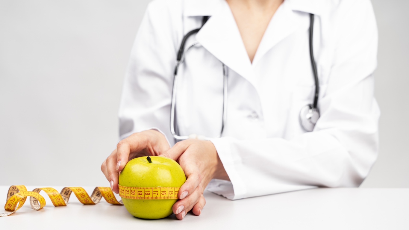 Женщина врач измеряет яблоко сантиметром 