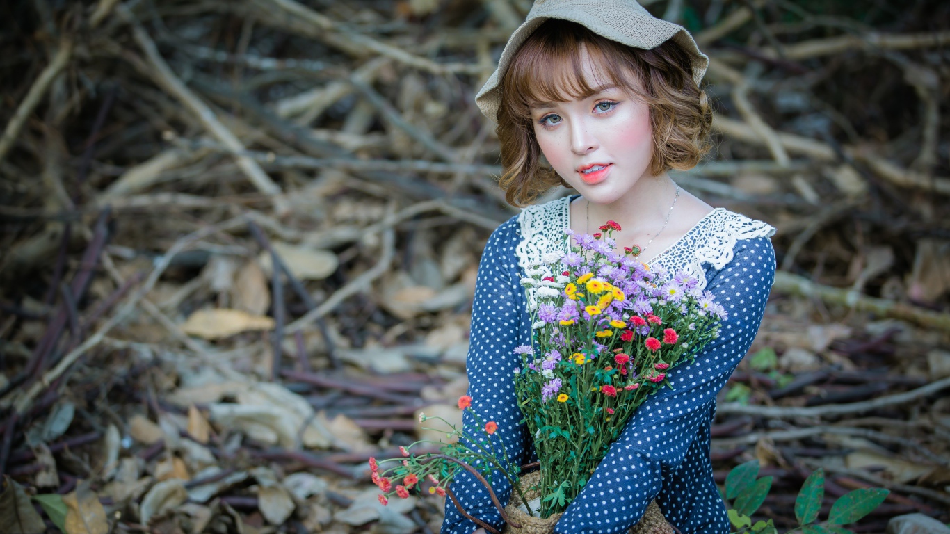 Молодая девушка азиатка с букетом цветов сидит на ветках