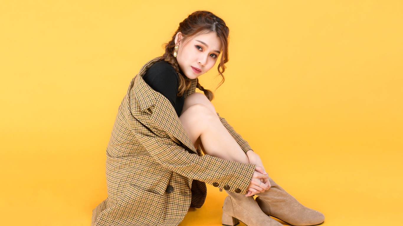 Девушка азиатка в пальто на желтом фоне 