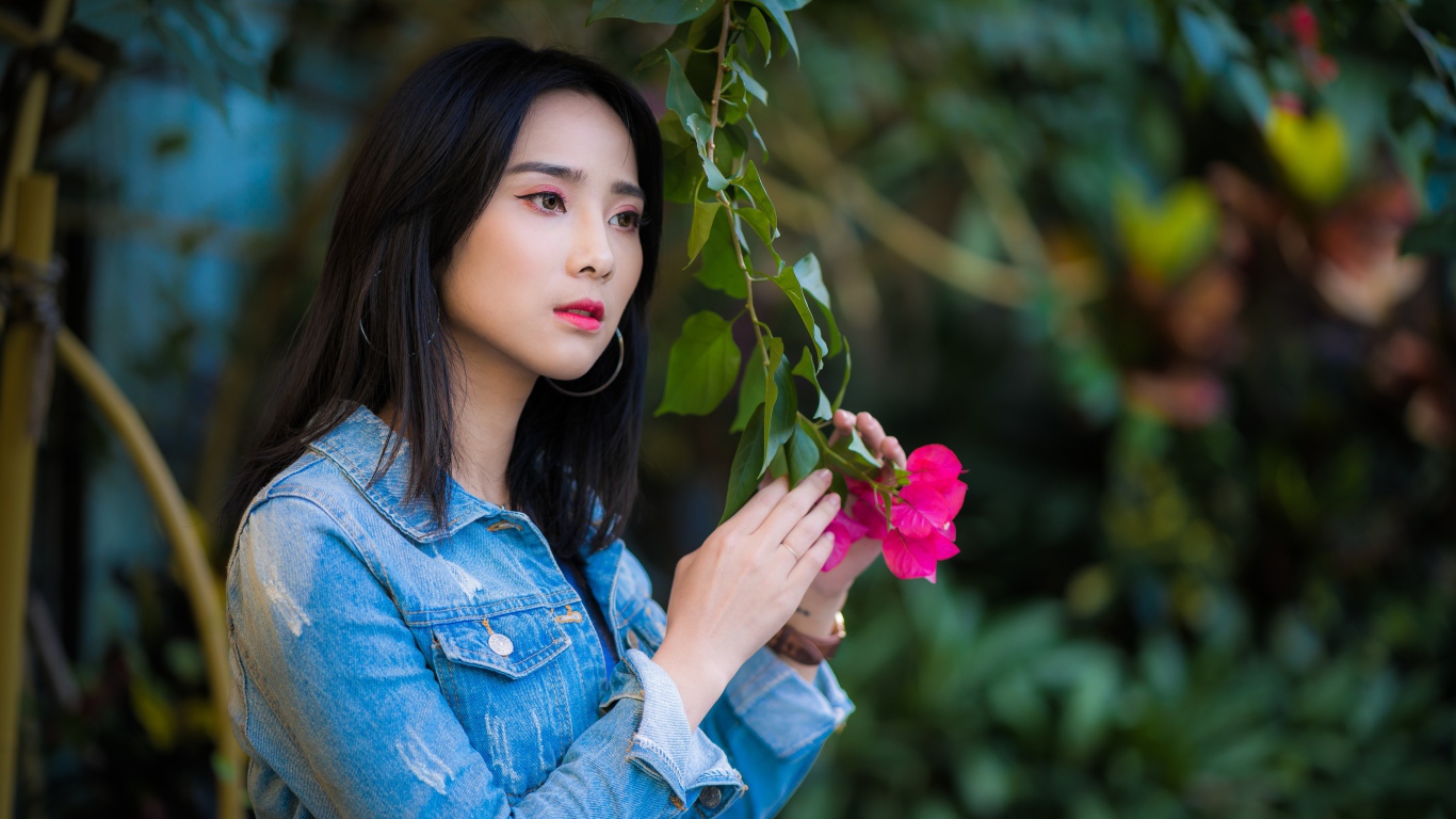 Девушка азиатка в джинсовой куртке в парке