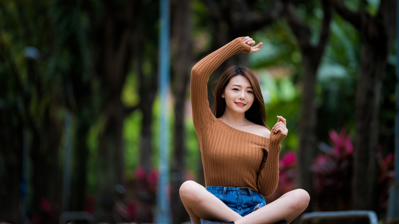 Девушка азиатка сидит в позе лотоса в парке 