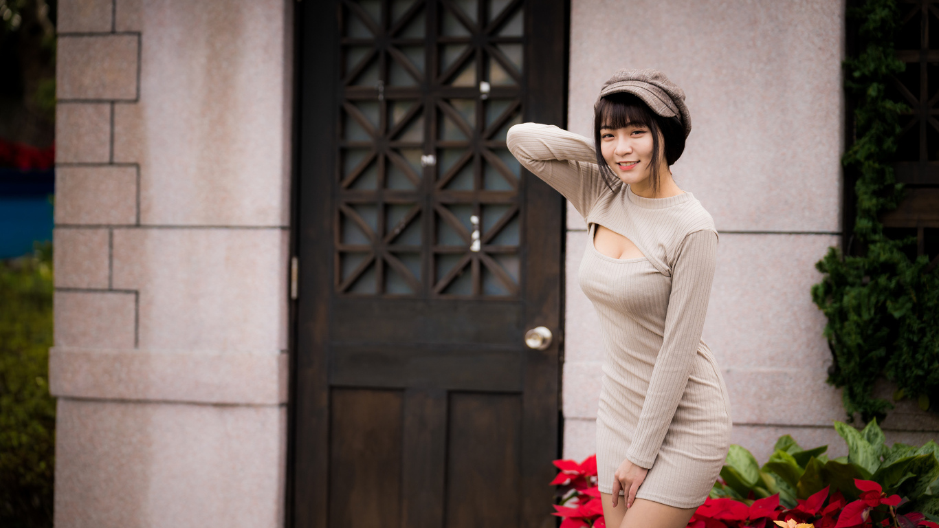 Красивая азиатка в платье стоит у двери 