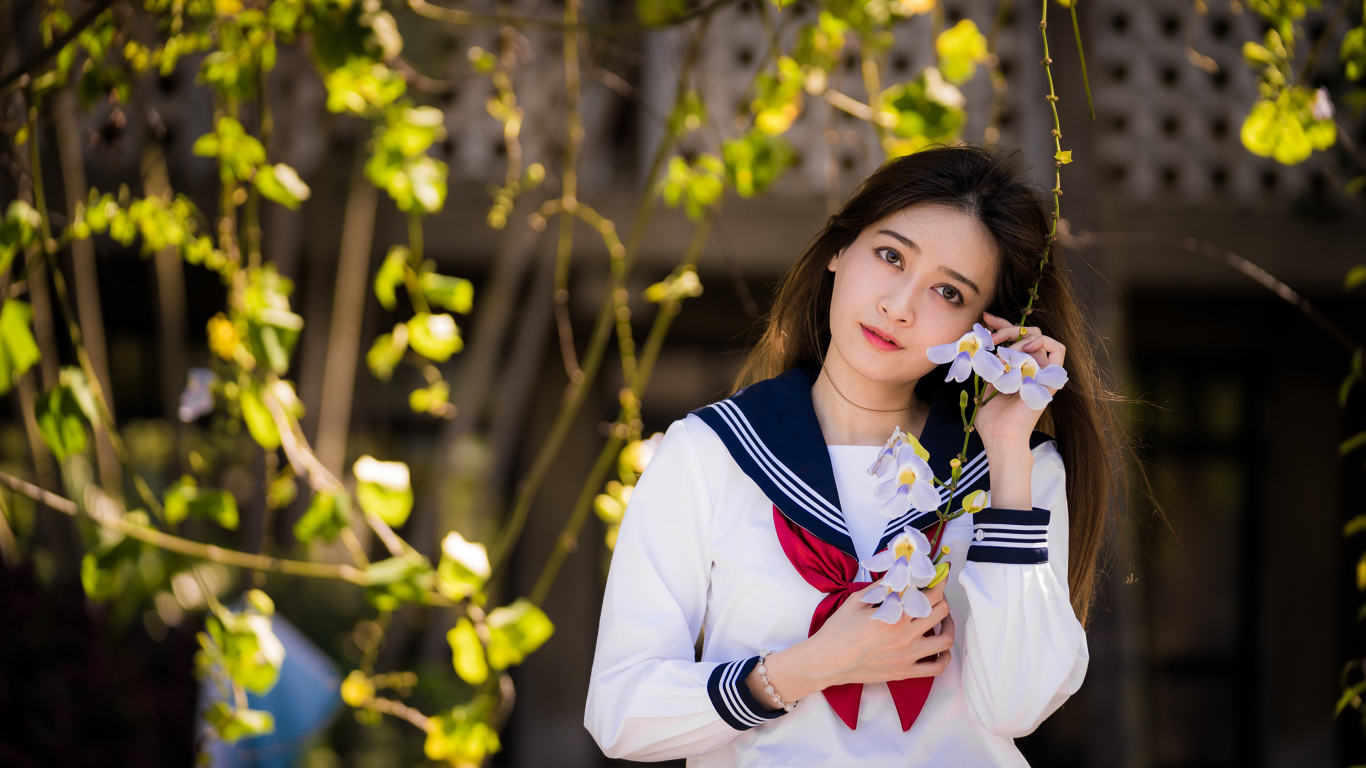 Красивая девушка азиатка в форме с цветами в руках 