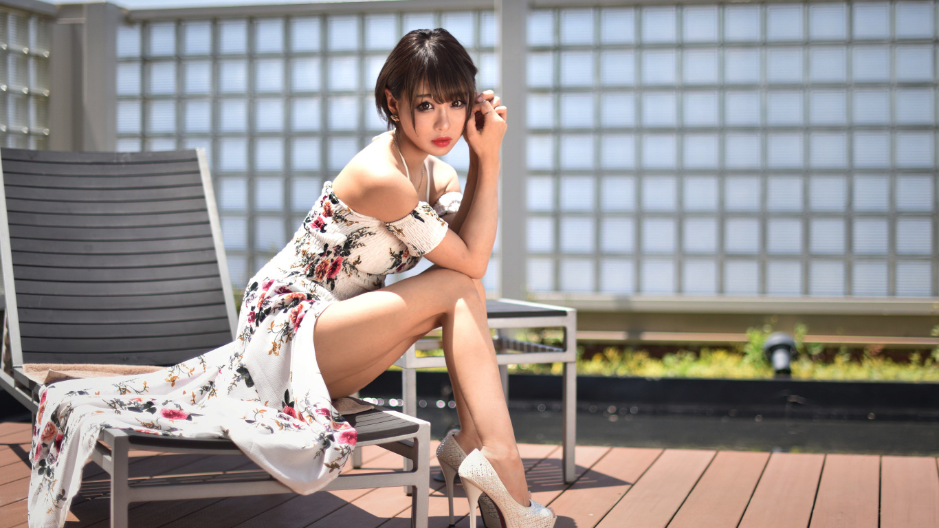 Красивая девушка азиатка сидит на шезлонге 