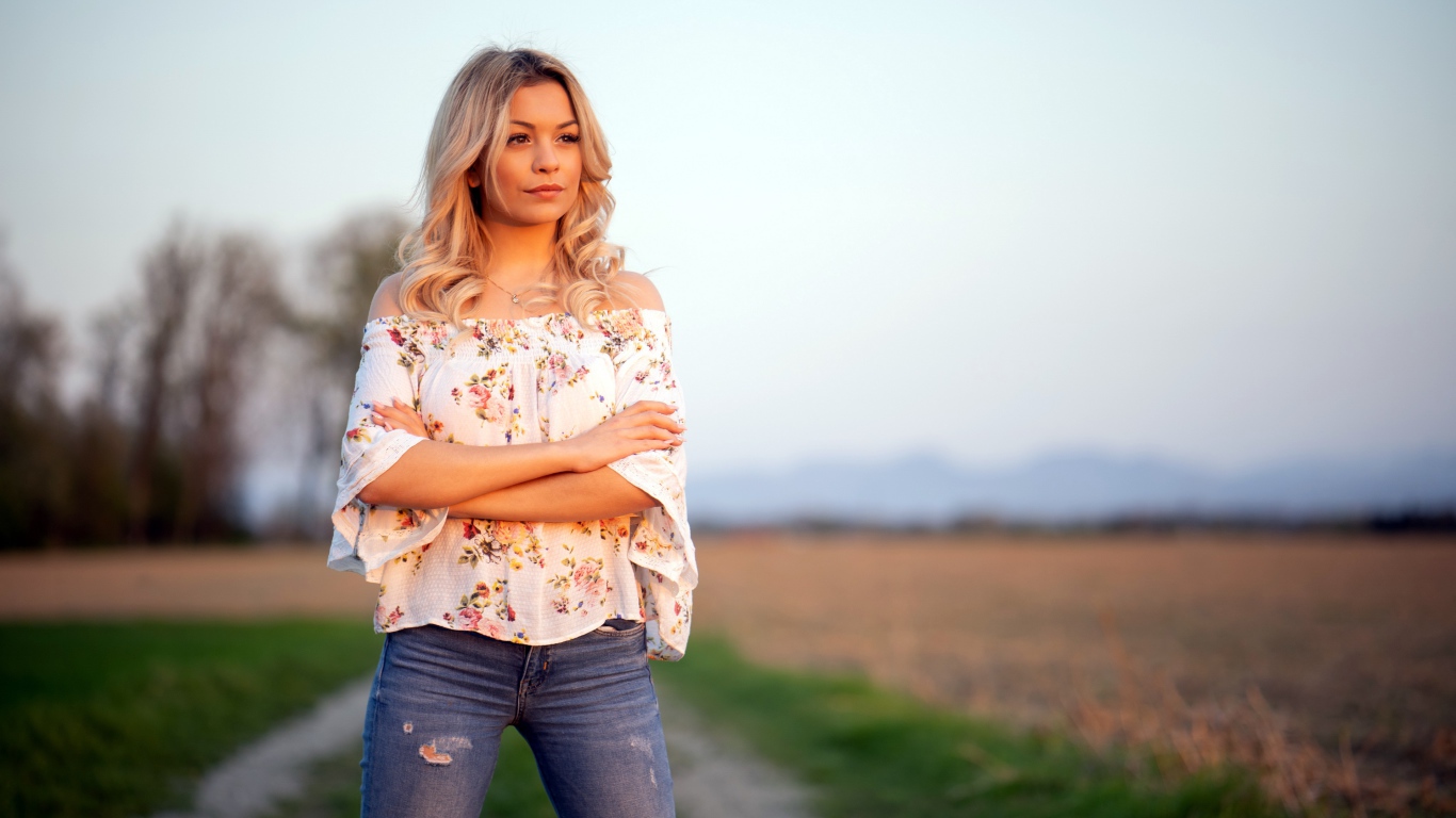 Красивая девушка блондинка в джинсах в поле