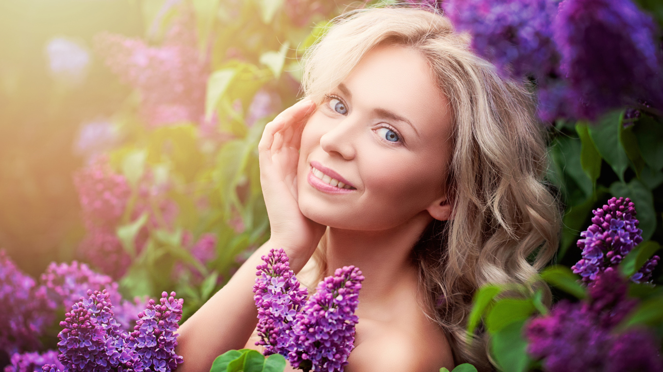 Красивая голубоглазая девушка блондинка в цветах сирени