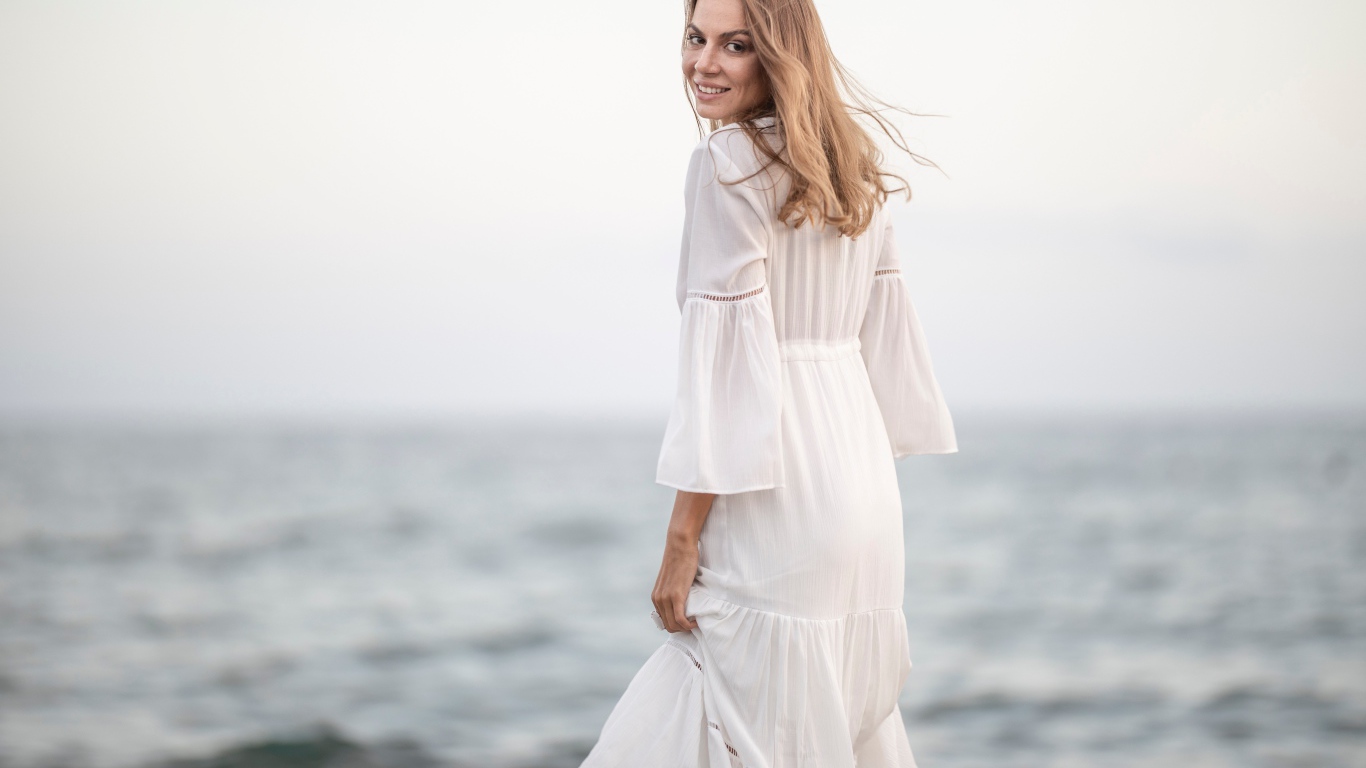 Красивая девушка в белом платье у моря