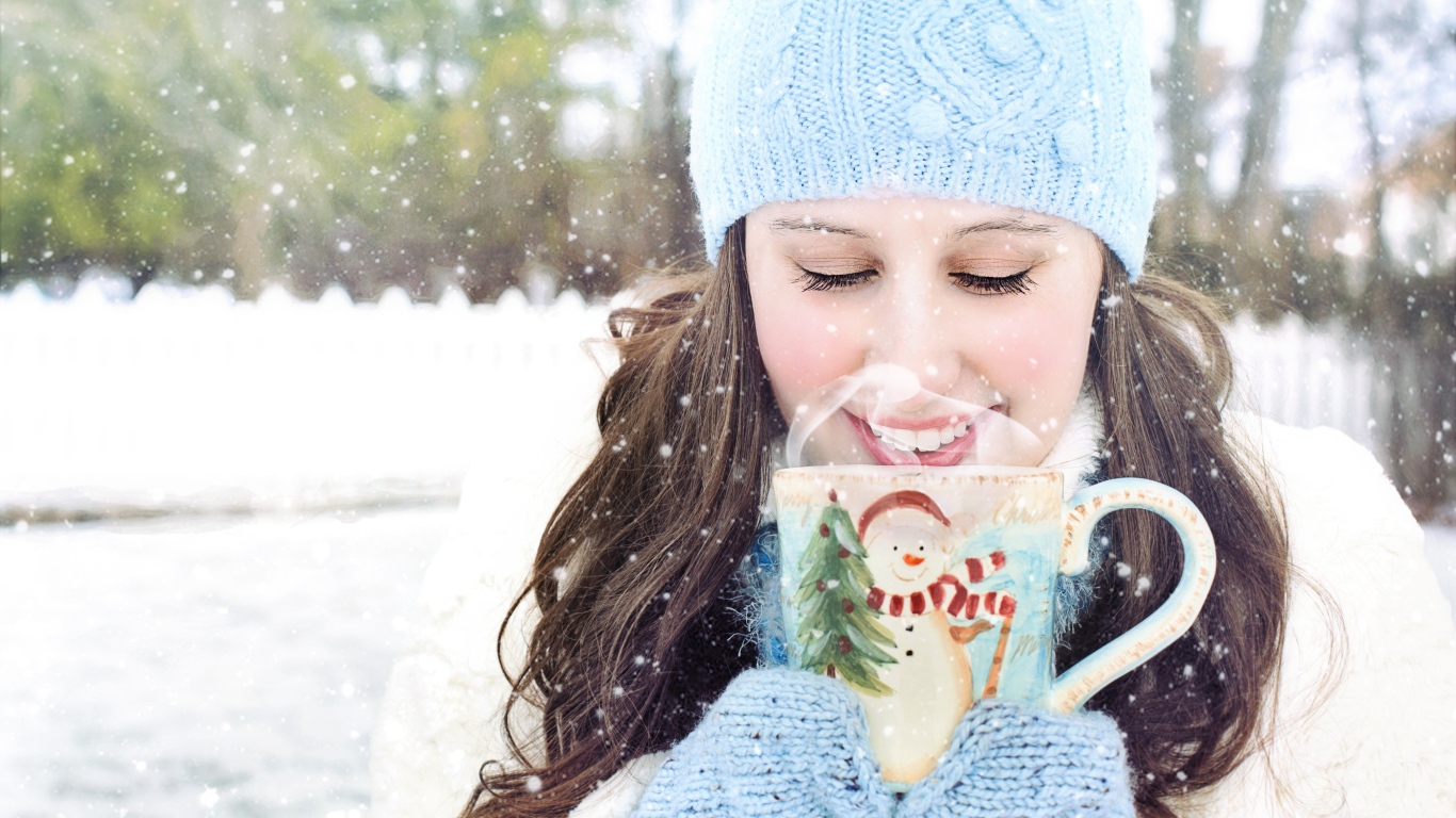 Красивая девушка с чашкой горячего кофе на улице зимой