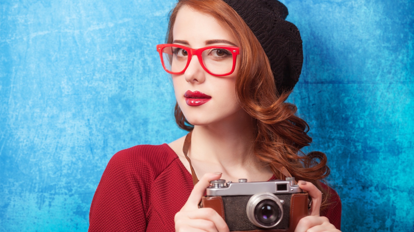 Красивая рыжеволосая девушка в черном берете с фотоаппаратом в руках 