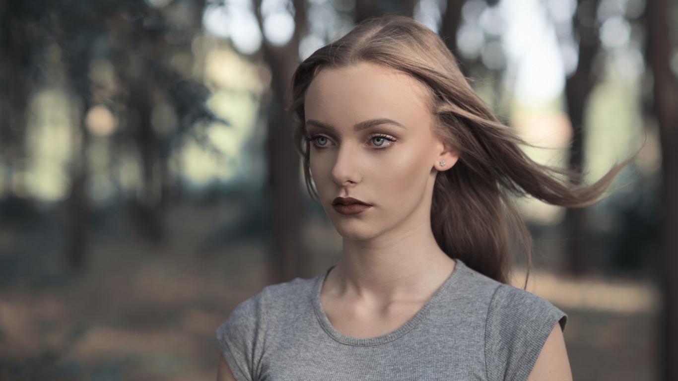 Голубоглазая девушка в серой майке в парке 