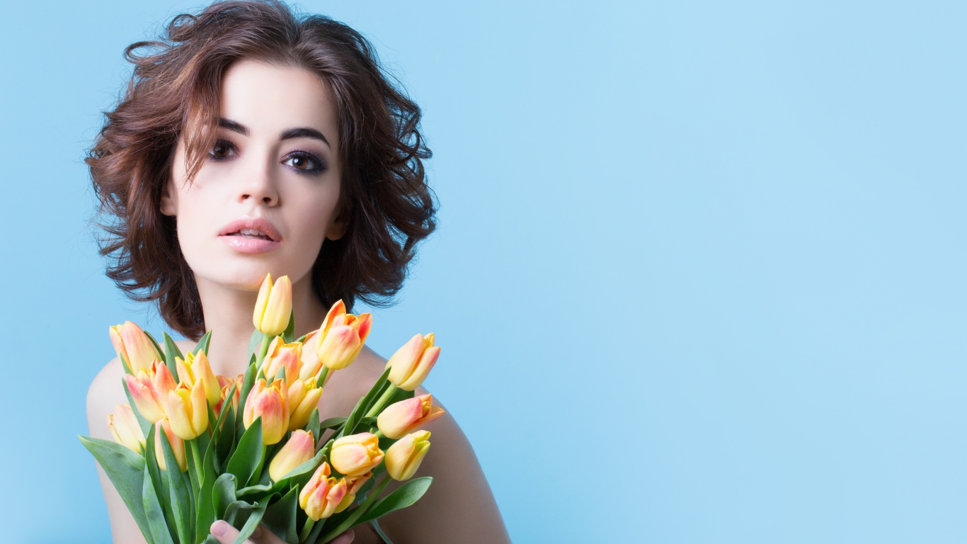 Кареглазая шатенка с букетом тюльпанов на голубом фоне