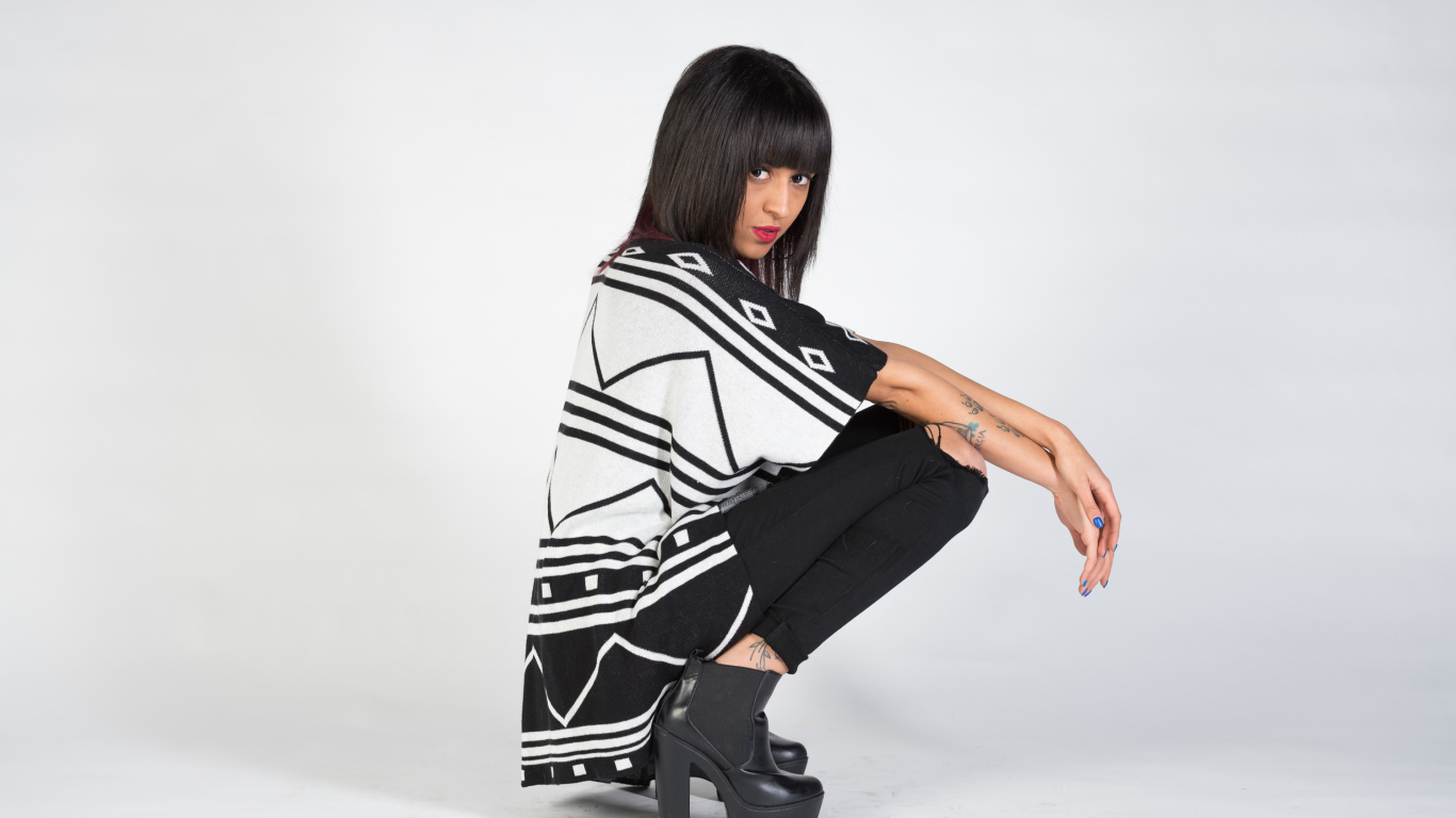 Брюнетка сидит на корточках 