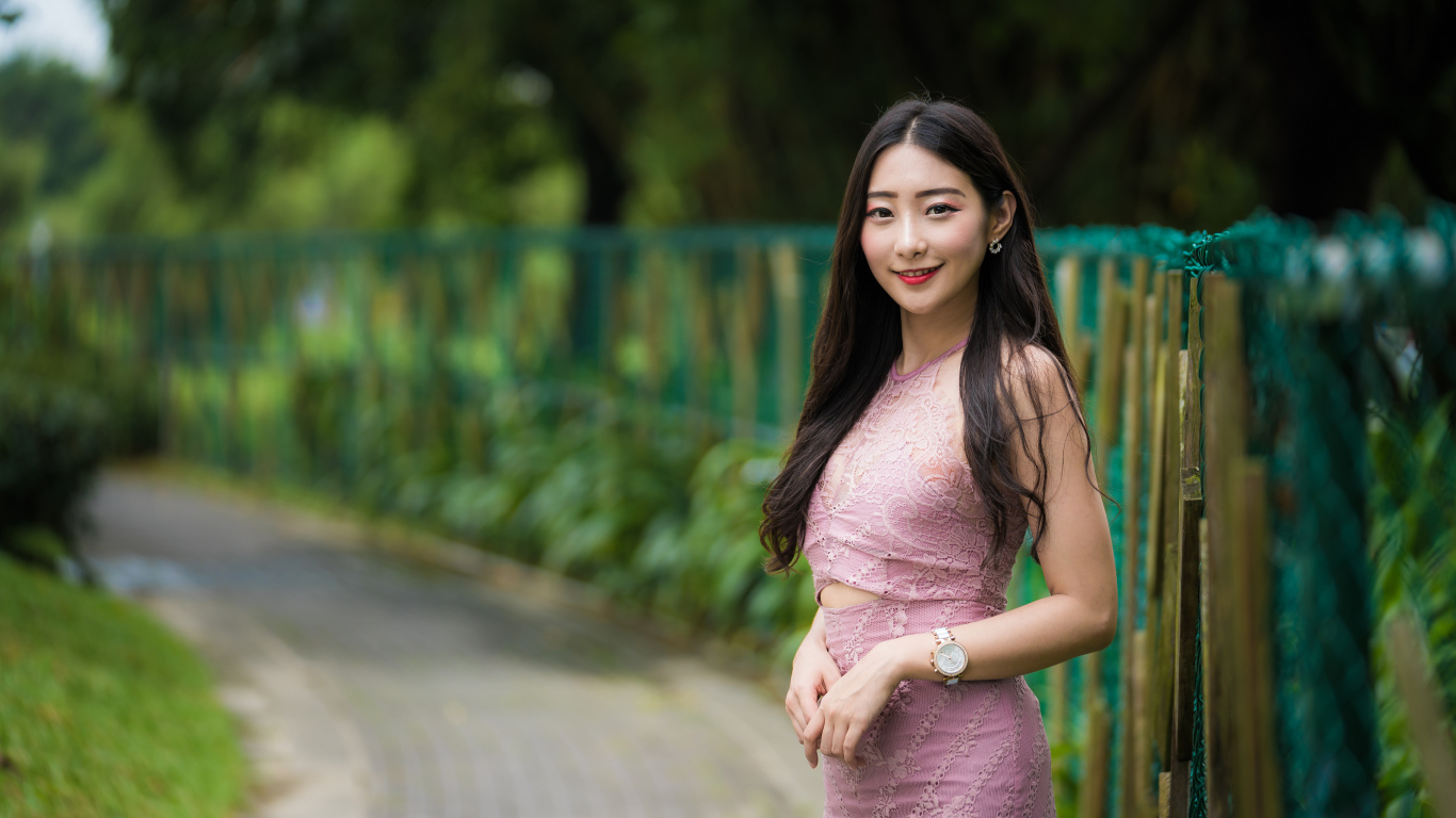 Милая улыбающаяся азиатка в костюме у забора
