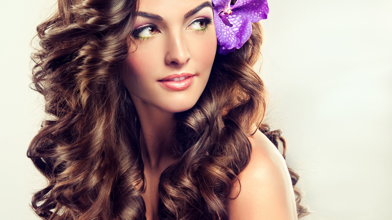 Цветок в красивых длинных волосах молодой девушки