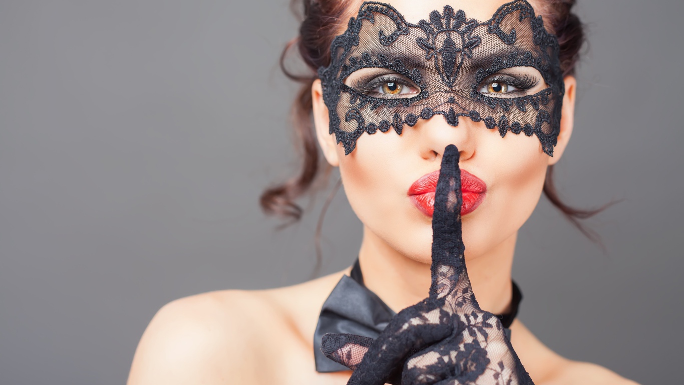 Девушка в черной маске с рукой в перчатке у лица