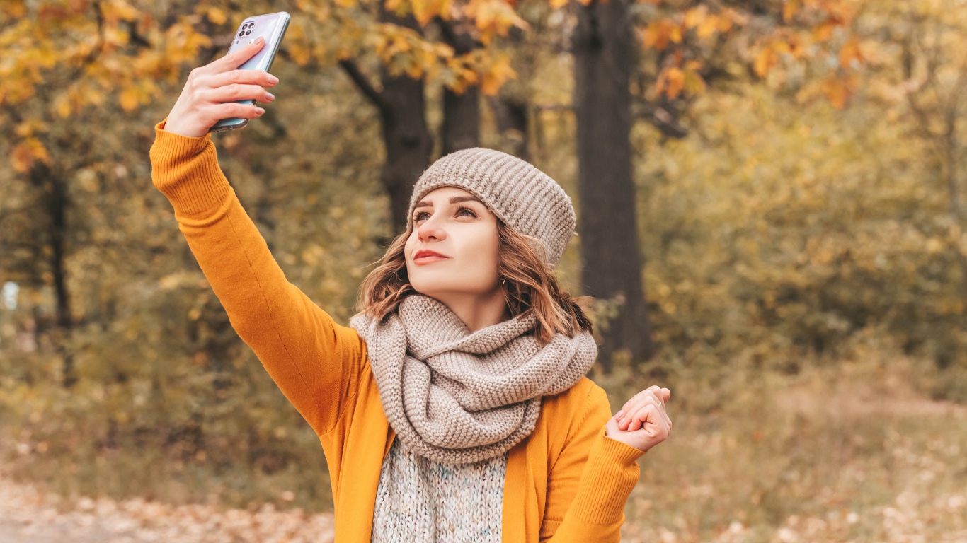 Девушка делает селфи на улице осенью 