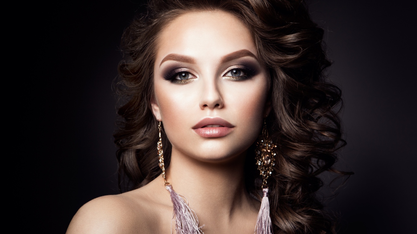 Девушка с прической с красивыми сережками на сером фоне 