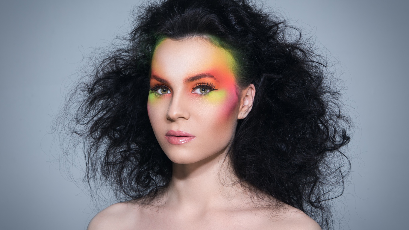 Девушка с начесом на волосах с ярким макияжем на сером фоне