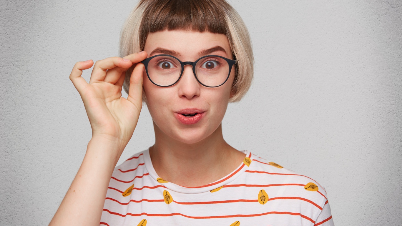 Девушка с короткой стрижкой поправляет очки 