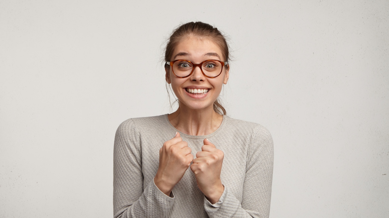 Радостная девушка в очках для зрения на сером фоне 