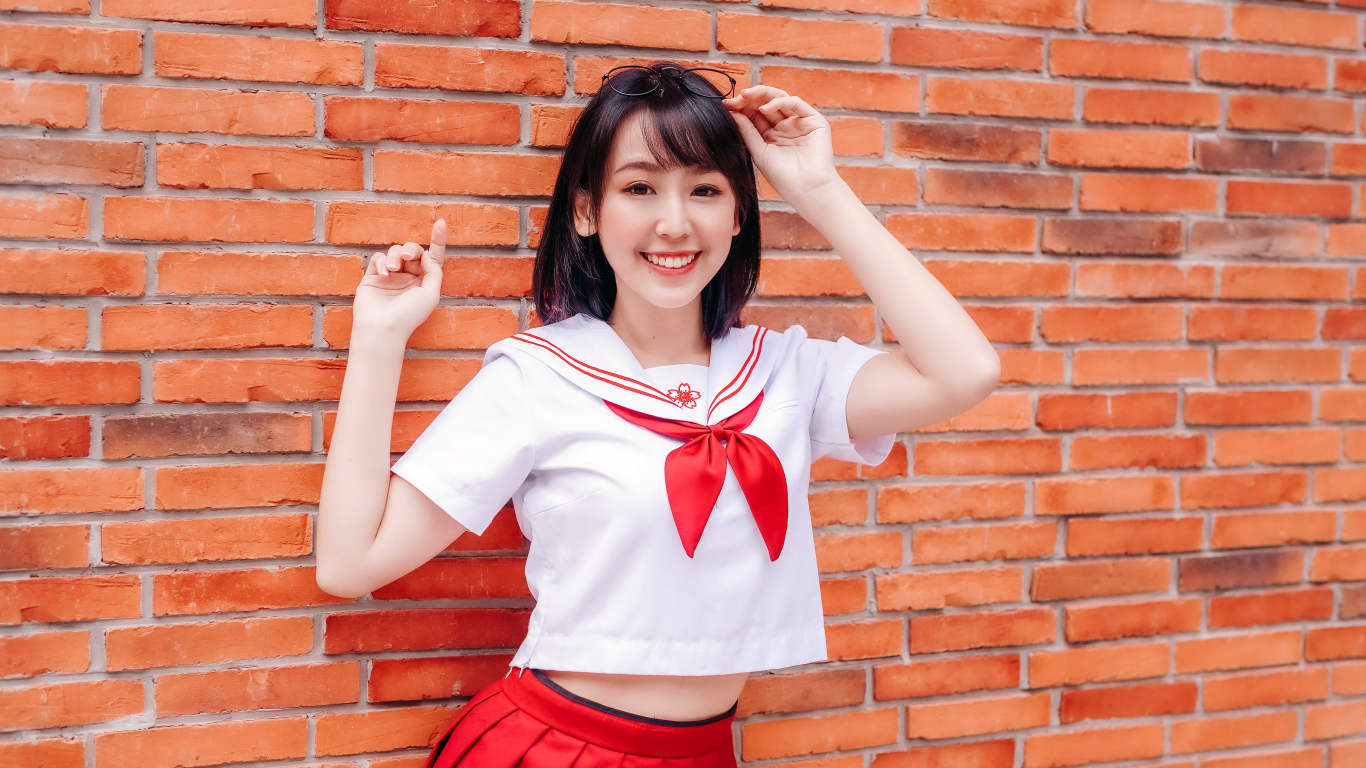 Улыбающаяся азиатка стоит у стены 