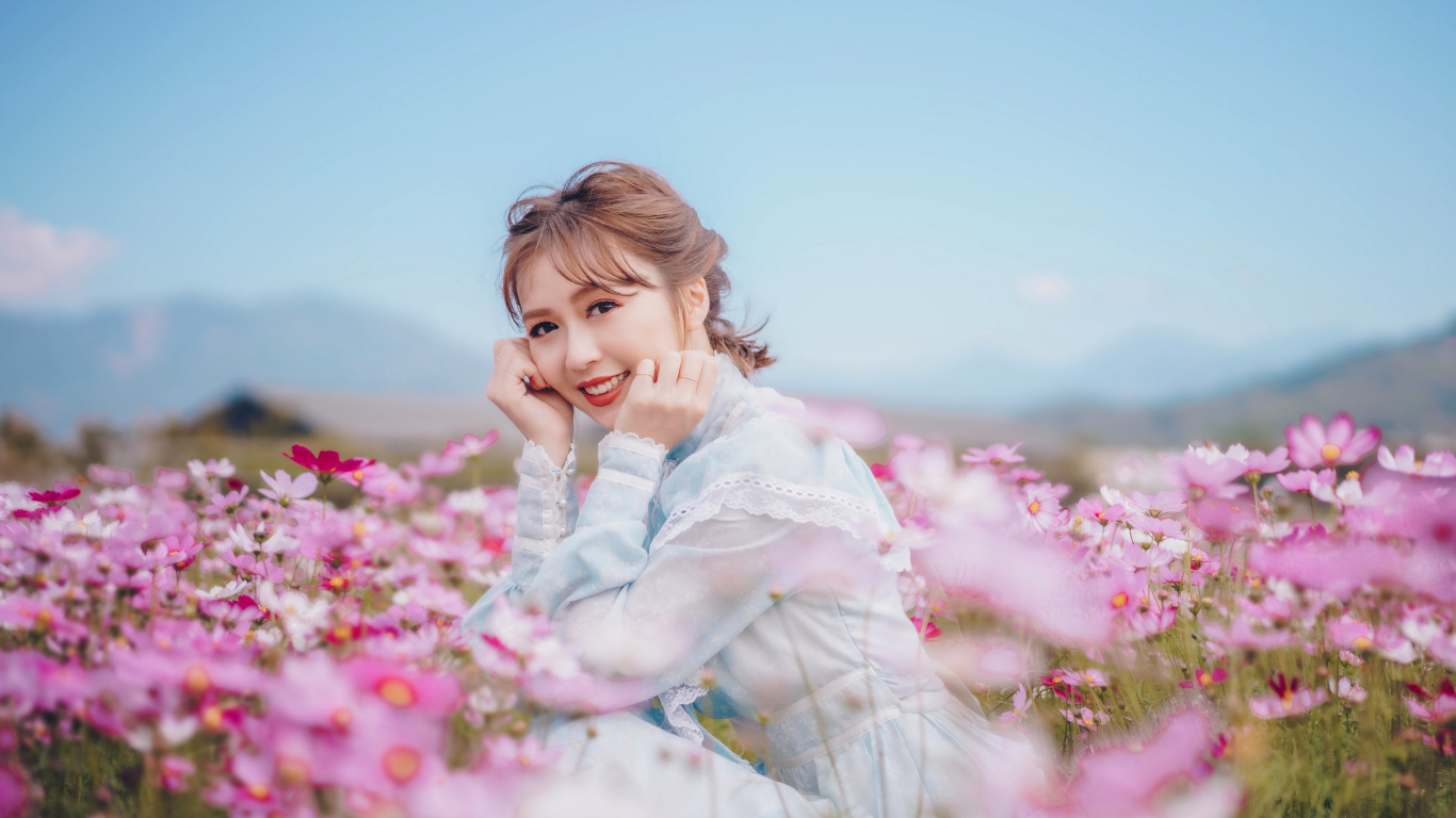 Улыбающаяся девушка азиатка на поле с цветами космеи 