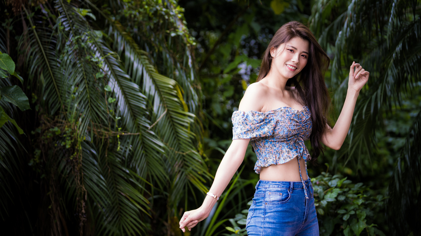 Улыбающаяся азиатка на фоне зеленых листьев