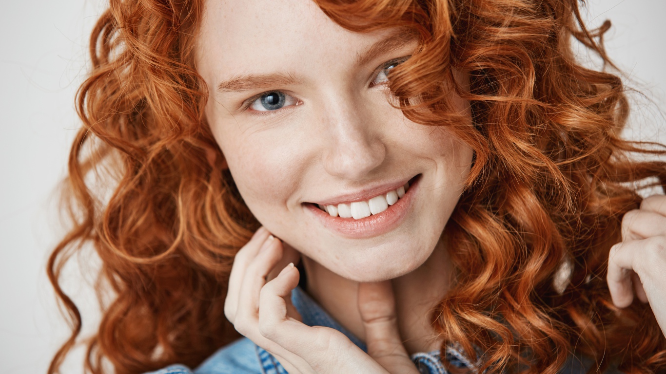 Улыбающаяся голубоглазая рыжеволосая девушка в джинсовой куртке 