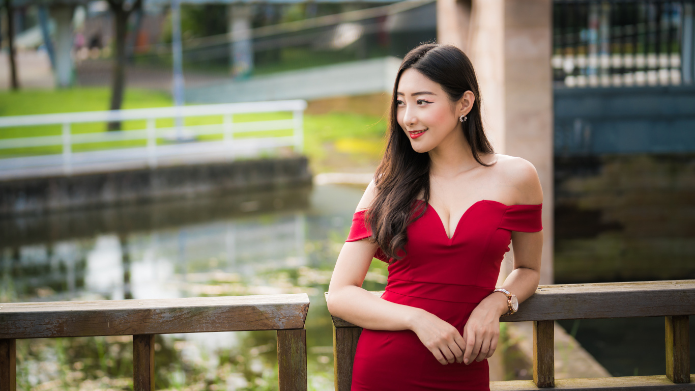 Улыбающаяся девушка в красном платье у перил 