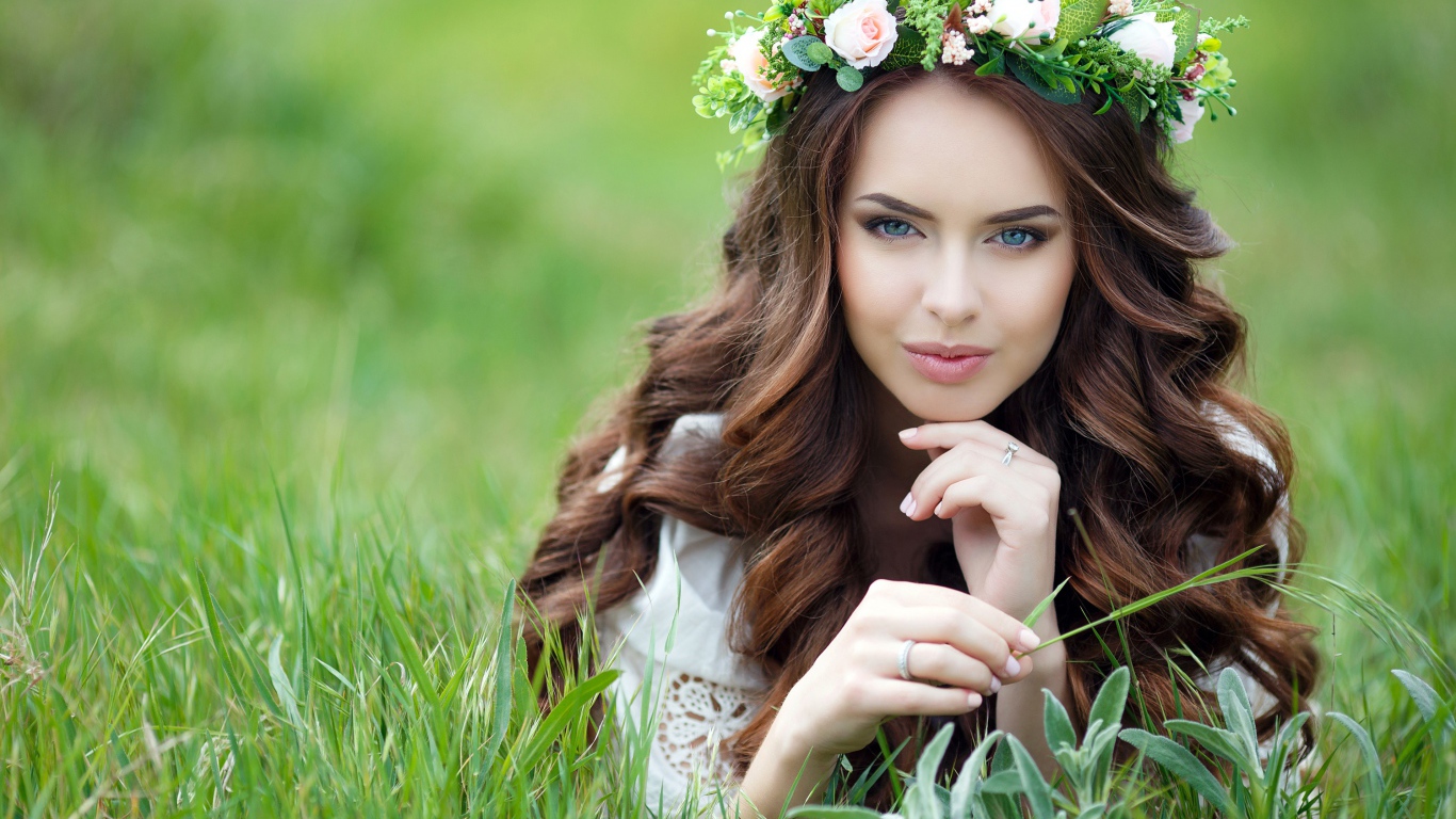 Эффектная настоящая девушка с венком на голове лежит на траве