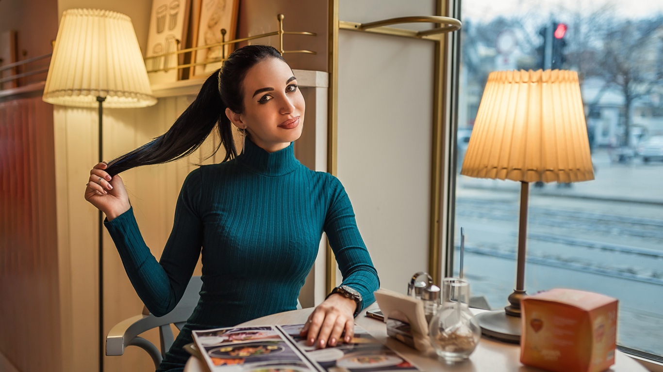 Стильная девушка в платье сидит в кафе у окна