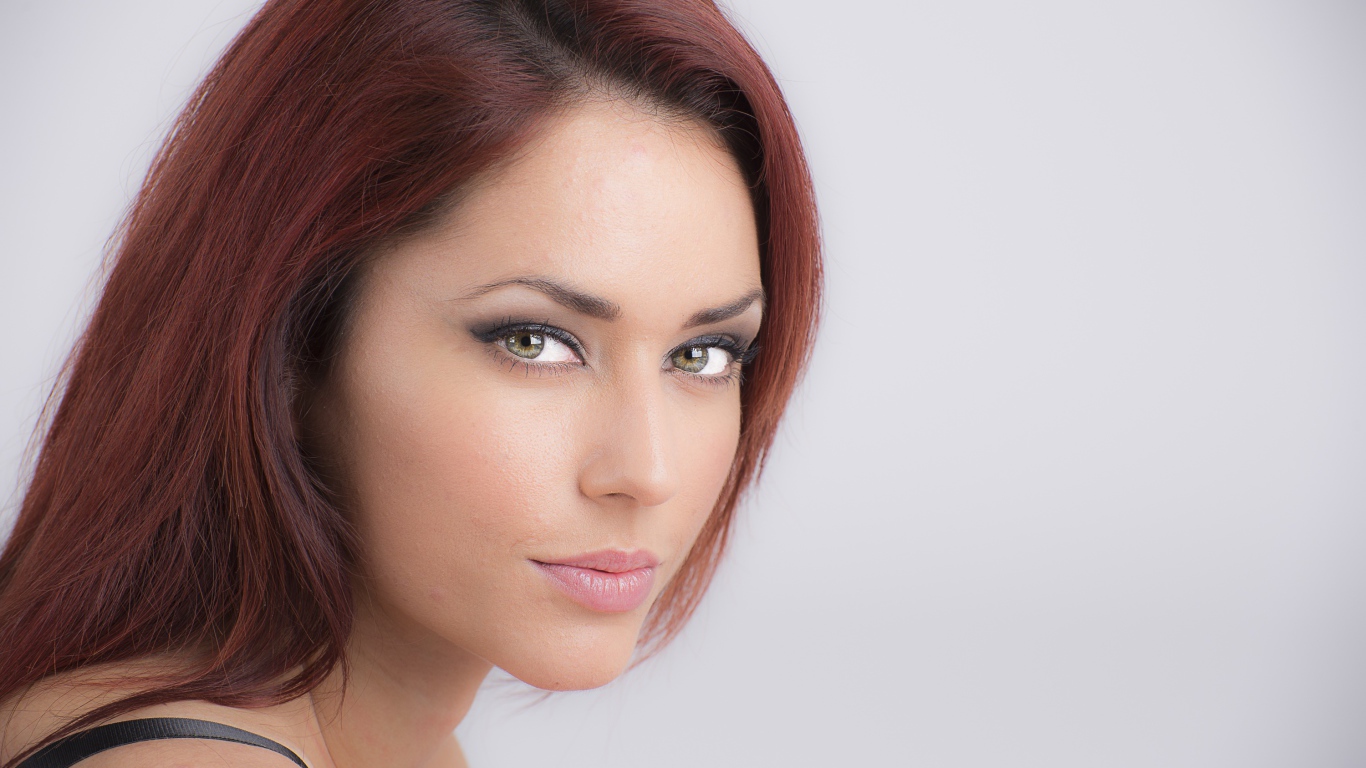 Лицо стильной девушки с зелеными глазами на сером фоне