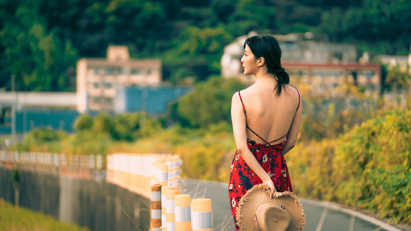 Молодая девушка азиатка в сарафане со шляпой в руке 