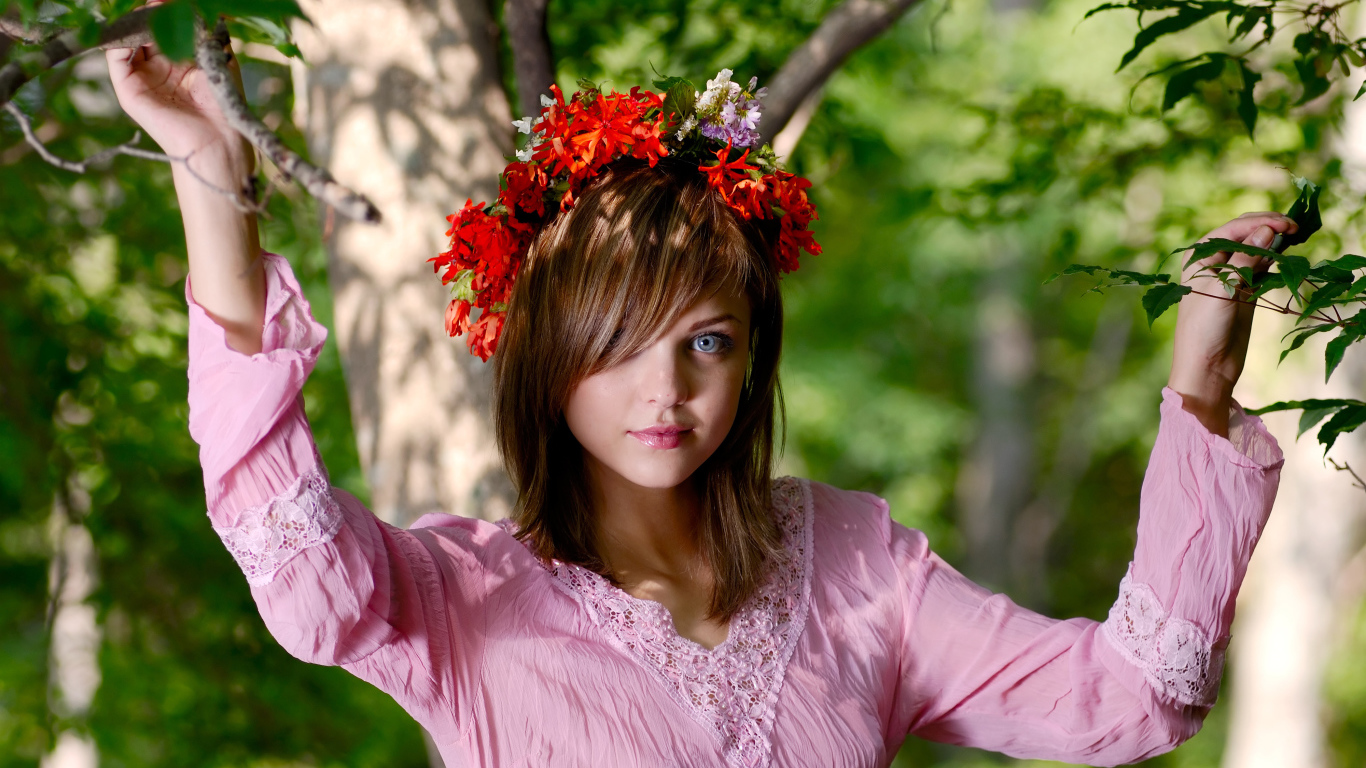 Молодая милая голубоглазая девушка с венком на голове у дерева