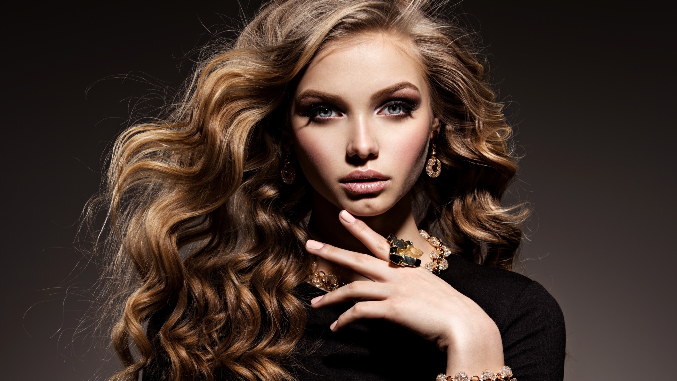 Молодая девушка в черном свитере с дорогими украшениями