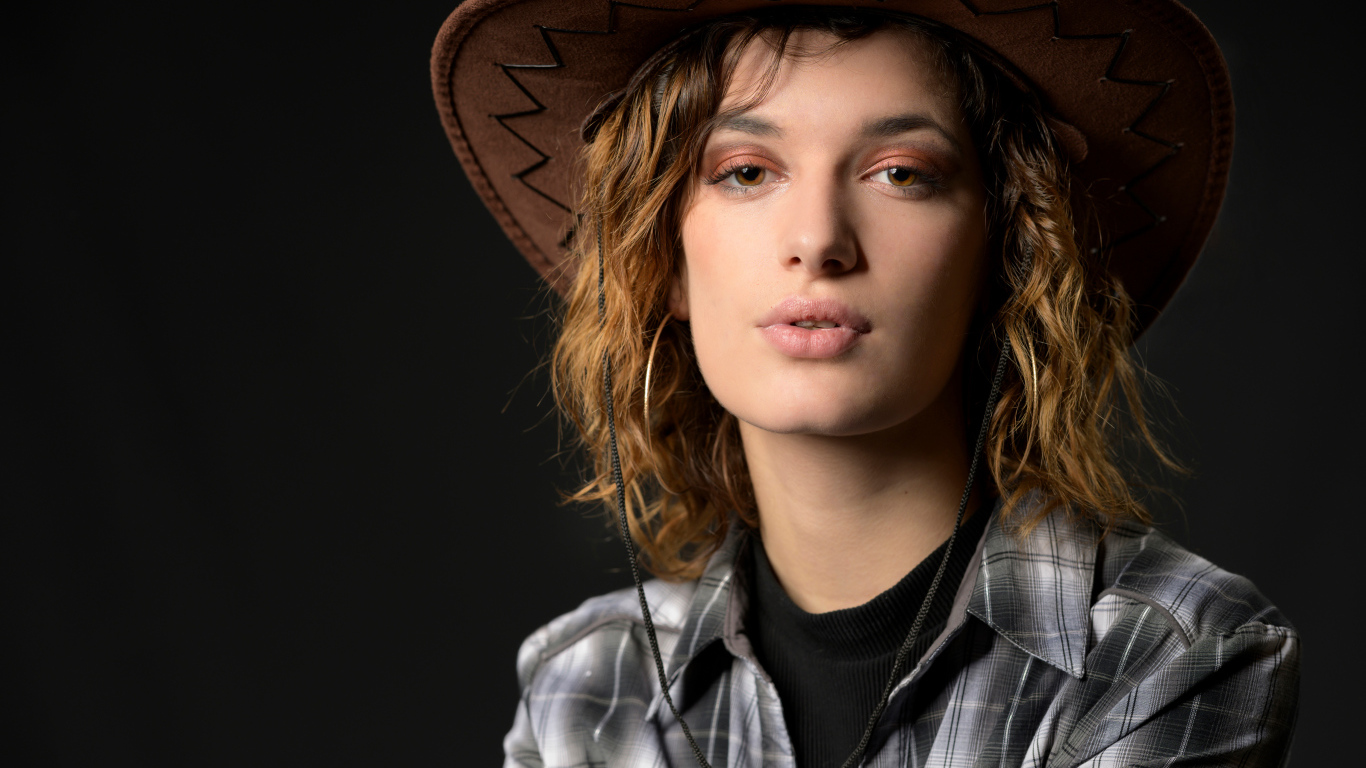 Молодая девушка в ковбойской шляпе на сером фоне