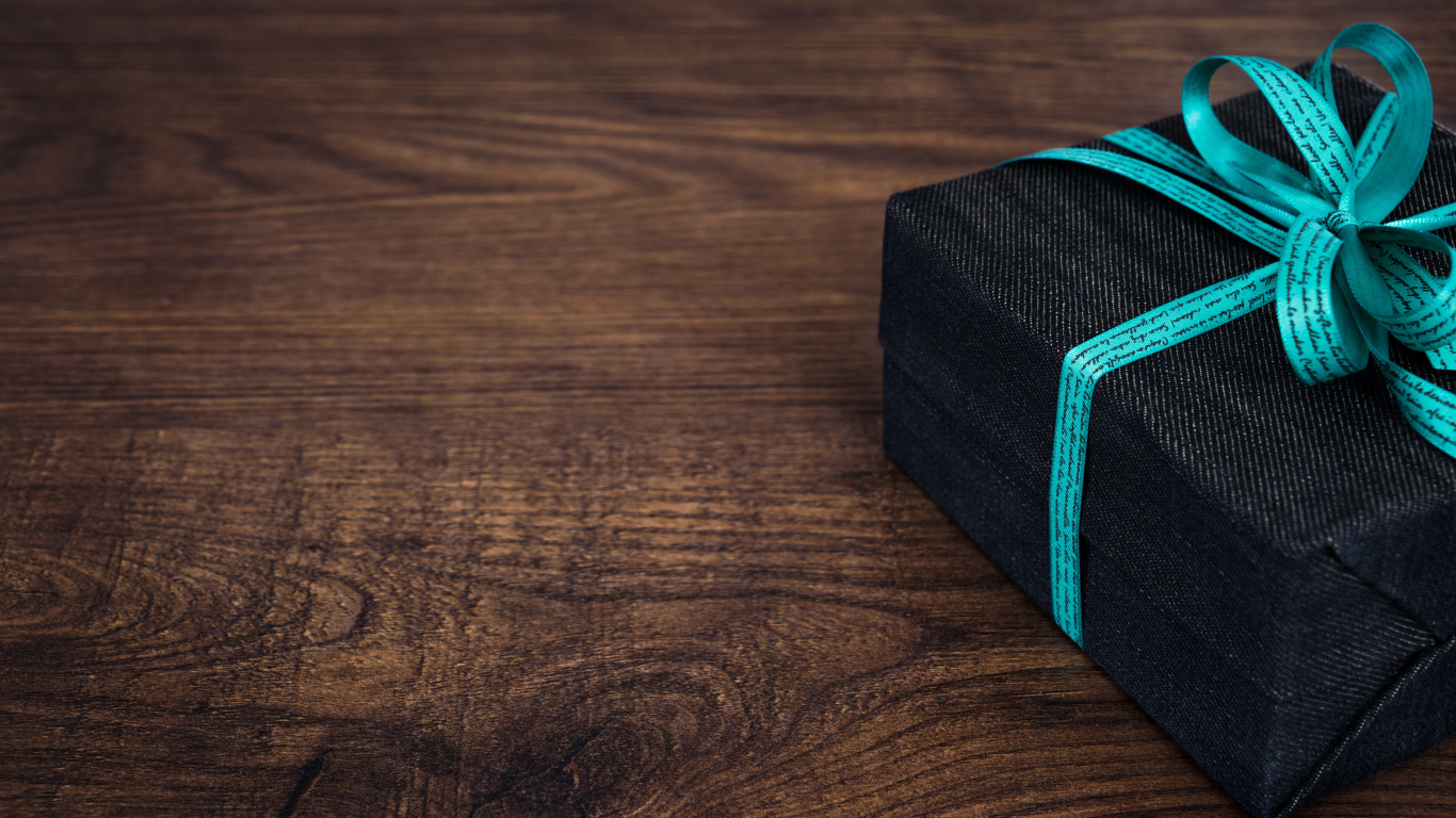 Подарок с синим бантом на деревянном столе 